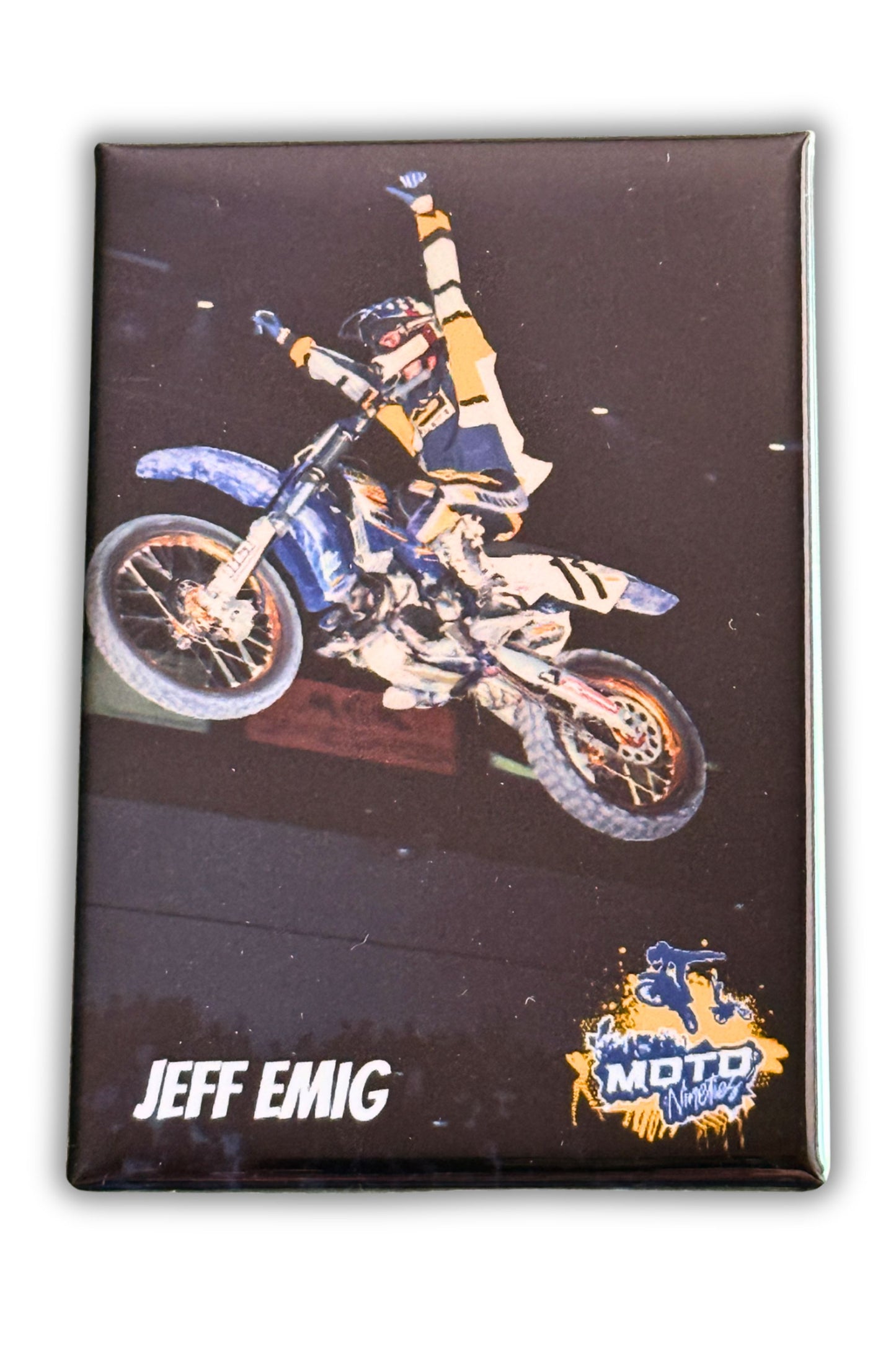 Jeff Emig riding a Yamaha motocross bike with both hands raised in celebration during a nighttime Supercross event.